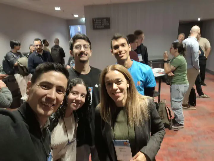 A group of conference participants smiling for a photo during a coffee break.