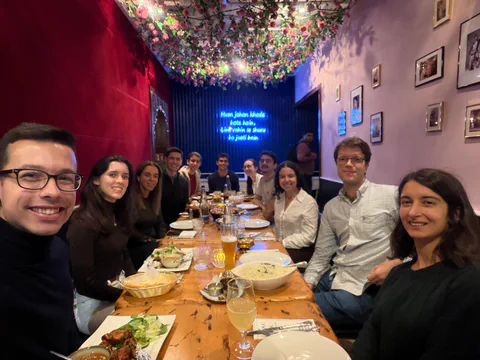 A group gathered for dinner in a restaurant with a colourful ceiling.
