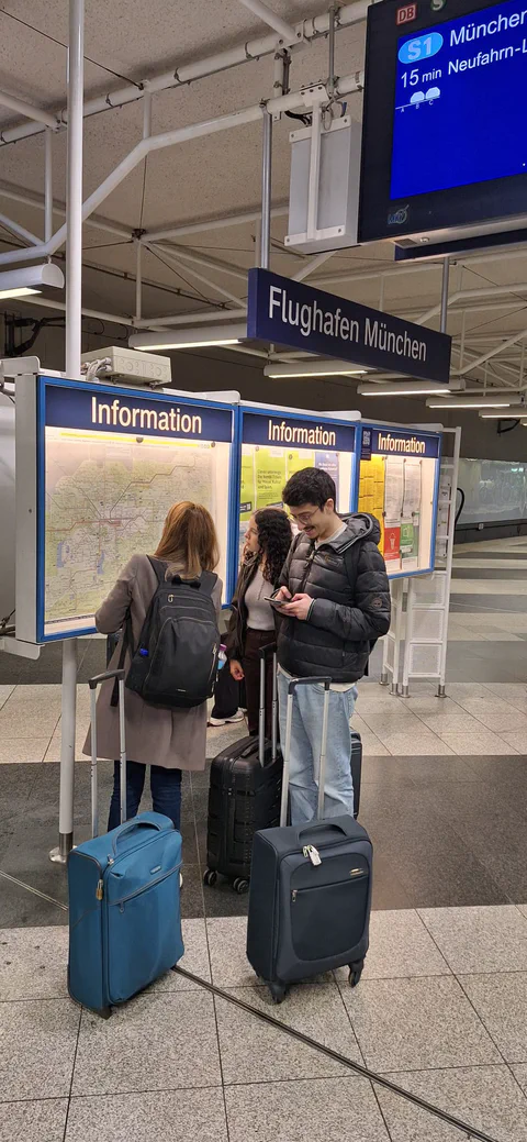 Travellers with suitcases at the airport information point in Munich.